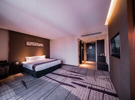 A modern hotel room with a large bed, a desk, and a seating area.