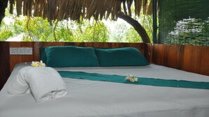 A neatly made bed with green pillows, a white towel, and a green cloth on the bed. - Beddegama Eco (Thissamaharama)