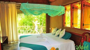 A bedroom with a bed, a window with curtains, a balcony, and a view of greenery. - Beddegama Eco (Thissamaharama)