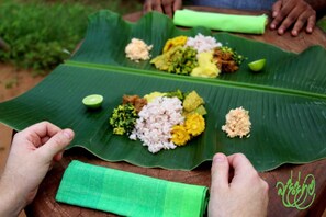 A meal served on a large green leaf, with various dishes including rice, vegetables, and a lime wedge. - Beddegama Eco (Thissamaharama)