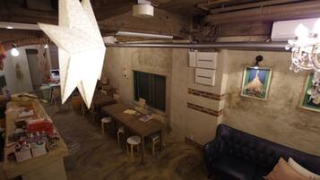 Un interior rústico con una mesa de comedor de madera, sillas, un sofá azul oscuro y una lámpara decorativa grande.