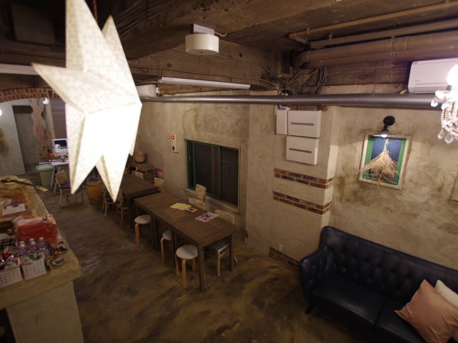 Un interior rústico con una mesa de comedor de madera, sillas, un sofá azul oscuro y una lámpara decorativa grande.