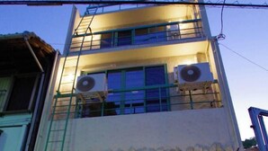 Een gebouw met twee verdiepingen, een groene deur en een klein portaal.