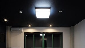 Een kamer met tatami vloerbedekking, een schuifglasdeur, inbouwspots en een airconditioner aan het plafond.