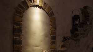 Een rustieke, met baksteen beklede schoorsteen met een klein plankje eronder, een wandlamp en een lantaarn.