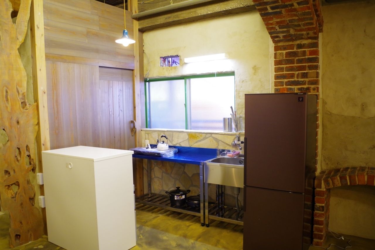 Cocina compacta con refrigerador, lavamanos y ventana.