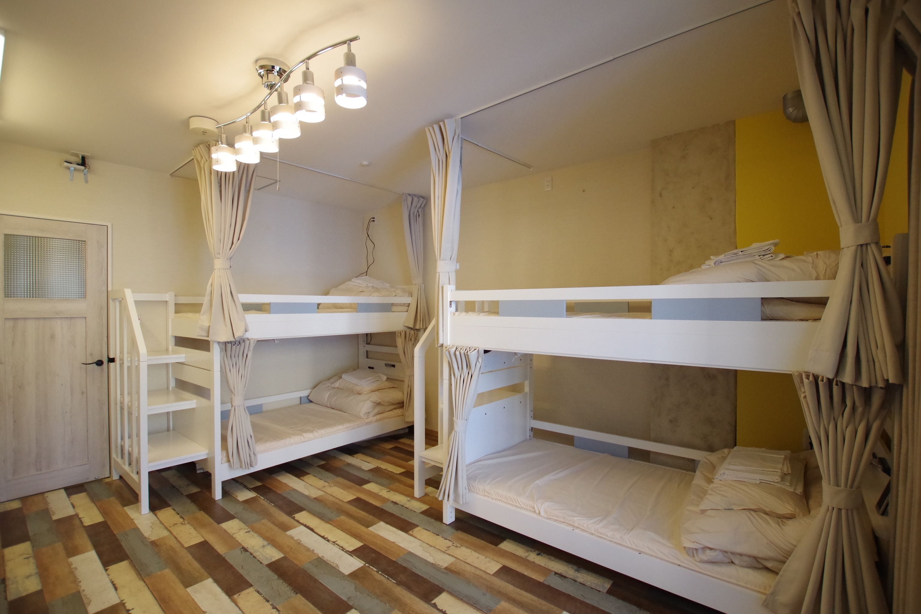A room with bunk beds, a wooden floor, and a curtain.