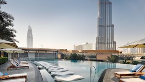 A rooftop pool with lounge chairs and umbrellas, overlooking a cityscape with tall buildings. - Kempinski The Boulevard Dubai (Dubai)