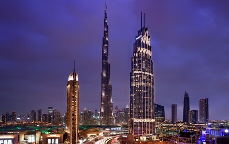 A cityscape at night with prominent skyscrapers, including the Burj Khalifa, and a busy highway with traffic.