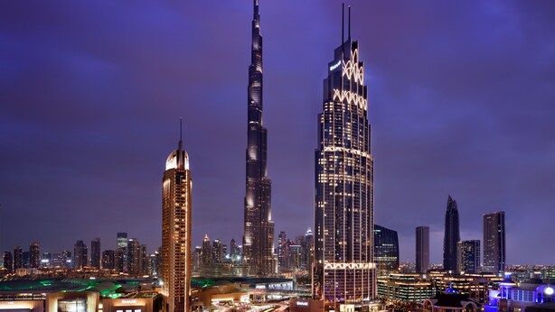 A cityscape at night with prominent skyscrapers, including the Burj Khalifa, and a busy highway with traffic. - Kempinski The Boulevard Dubai (Dubai)
