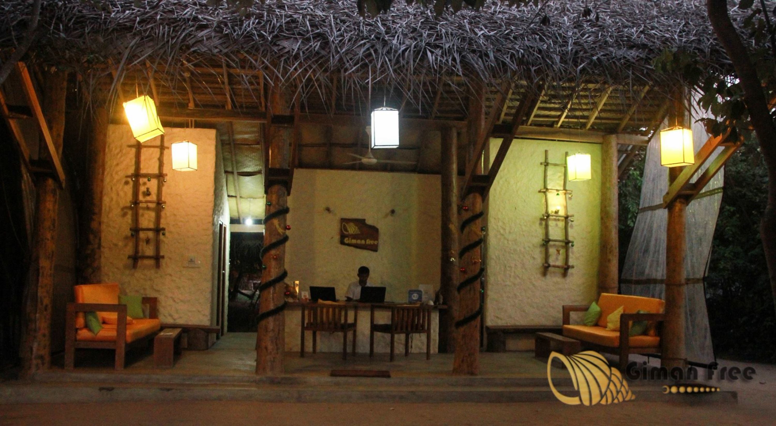 A rustic outdoor seating area with wooden furniture and hanging lanterns, a wooden ladder, and a sign on the wall.
