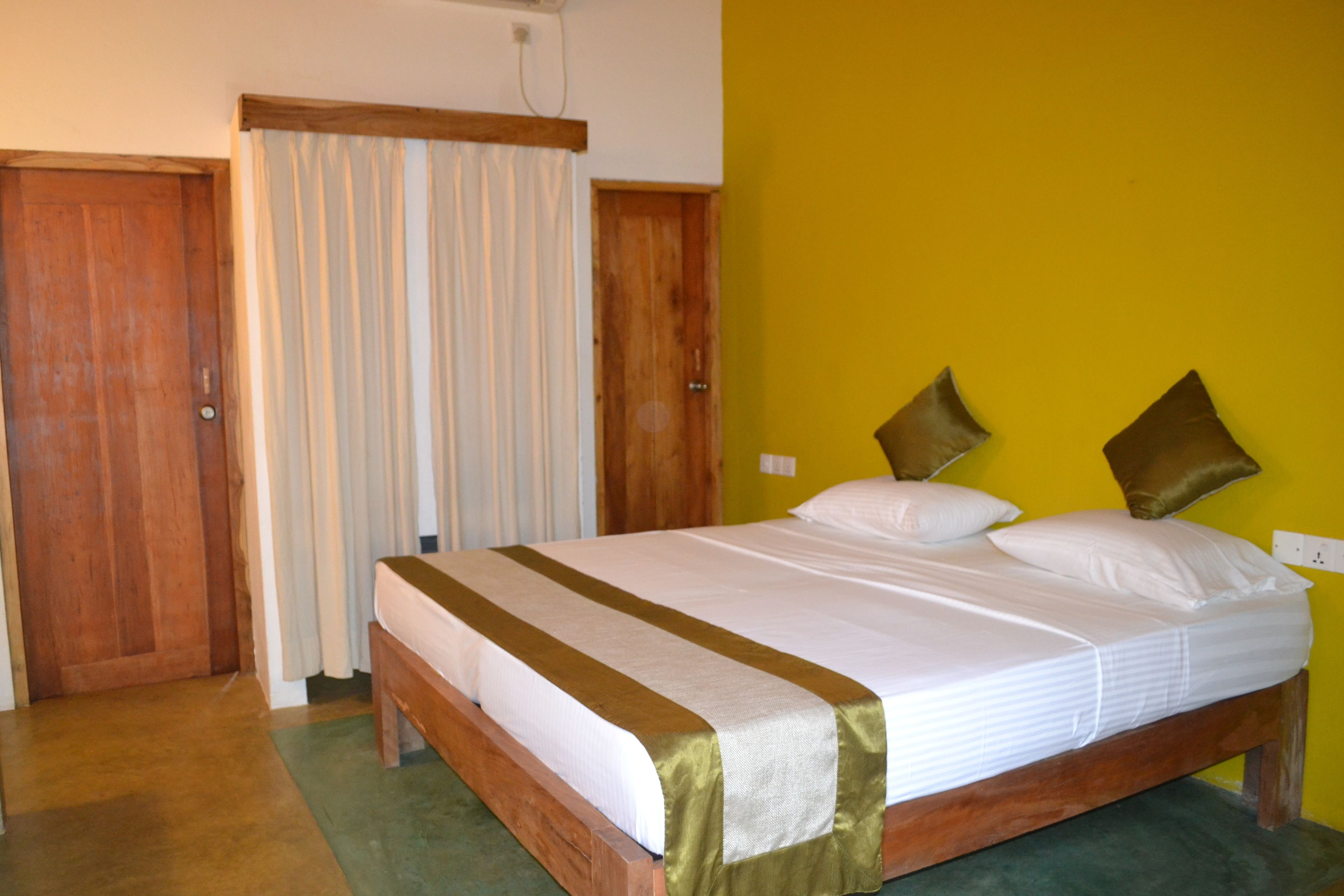 A bedroom with a wooden bed, white bedding, a green and white striped bed runner, and two brown pillows.