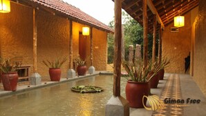 A traditional building with a tiled roof, potted plants, and a water feature.