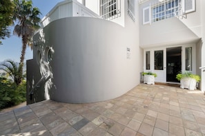 Um edifício moderno com fachada curva, placa de recepção e plantas em vasos na entrada.