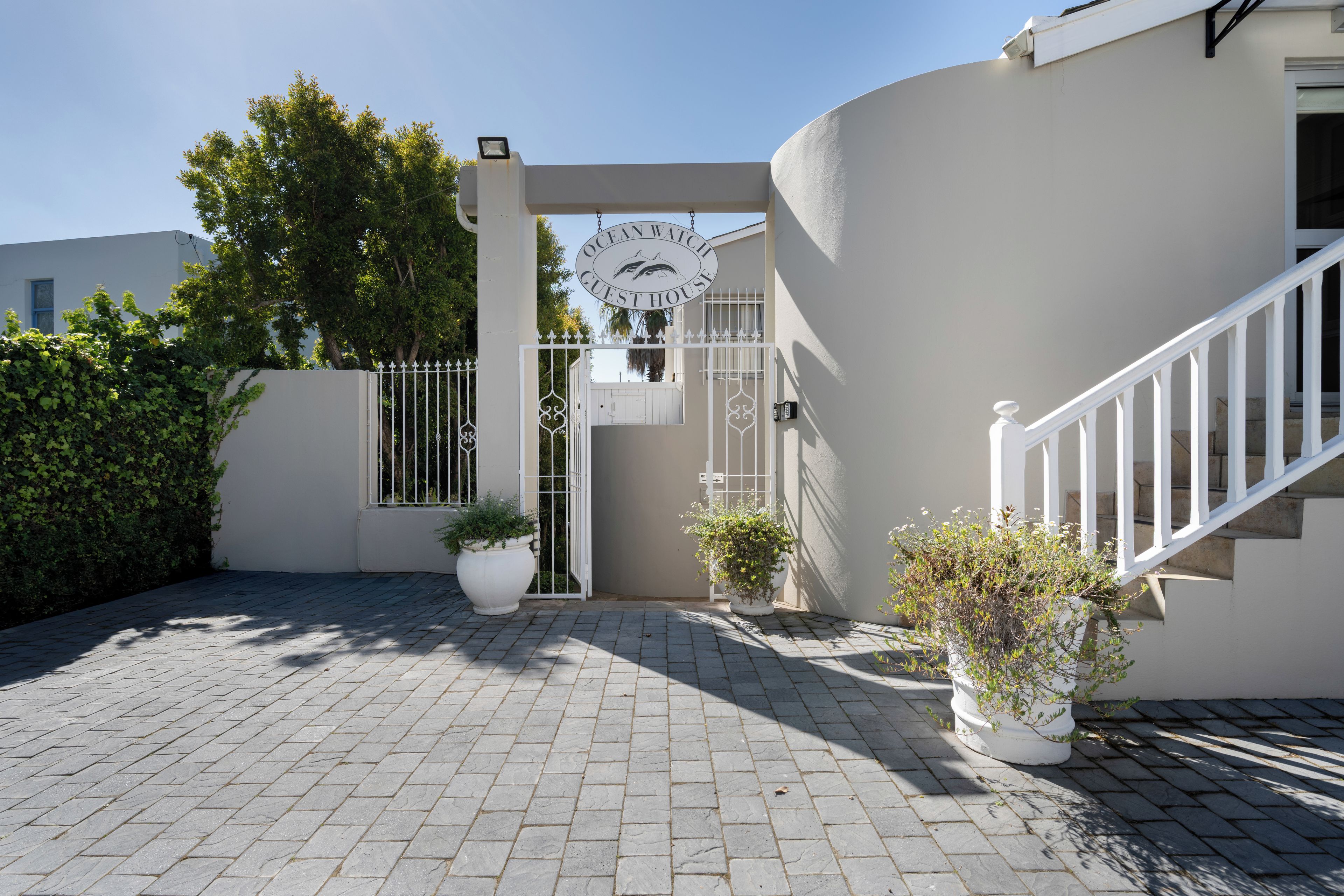 A gated entrance to a property with a sign reading 'Ocean Watch Guest House.'