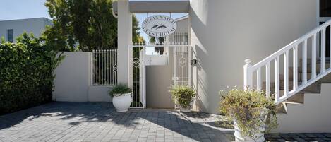 A gated entrance to a property with a sign reading 'Ocean Watch Guest House.'