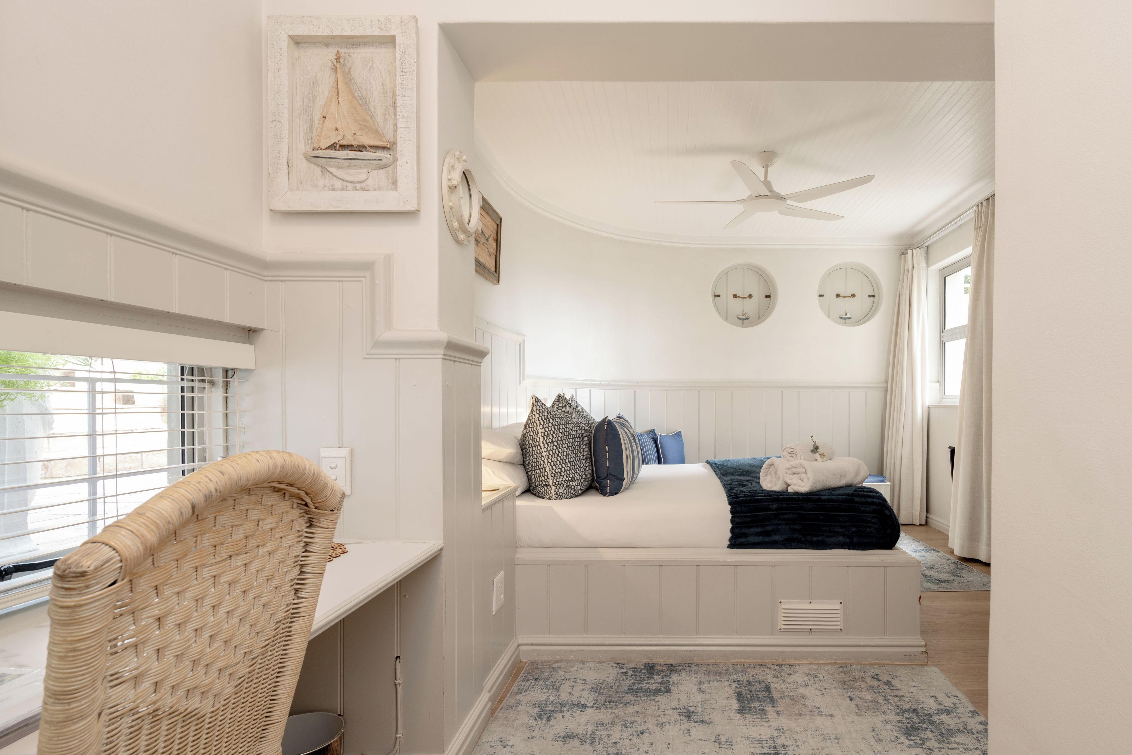 A bedroom with a bed, a ceiling fan, and a window with blinds.