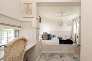 A bedroom with a bed, a ceiling fan, and a window with blinds.
