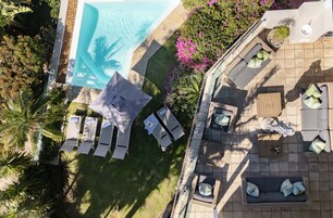 Un área de piscina en la azotea con sillas de descanso, un pequeño espacio de estar y abundante vegetación.