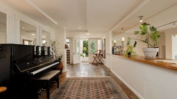A spacious hallway with a piano, a large mirror, and a potted plant.