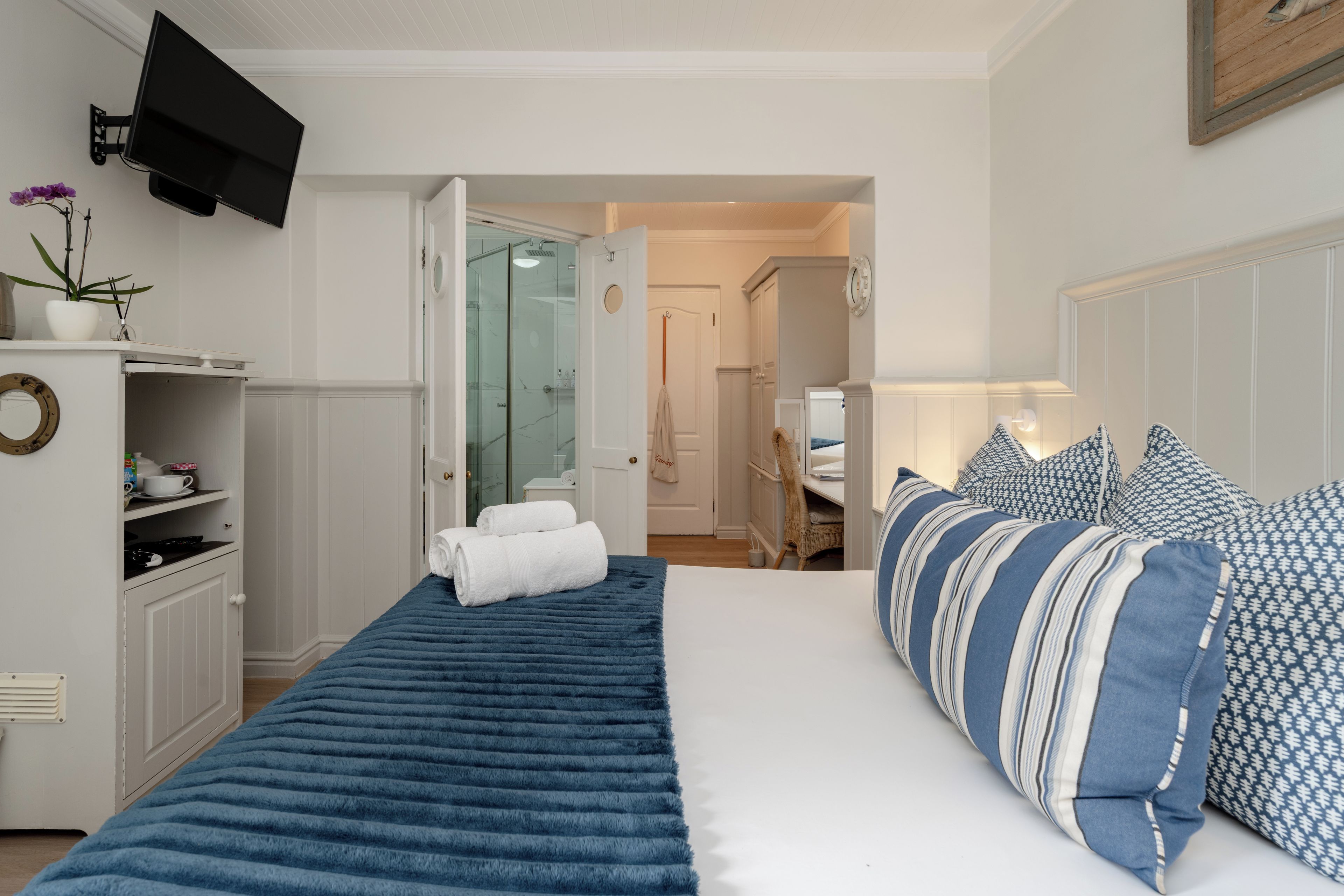 A hotel room with a bed, a TV, a bathroom, and a small kitchenette.
