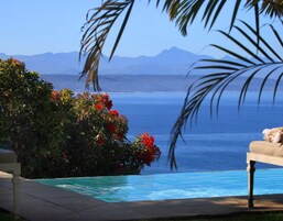 Una piscina al aire libre, sombrillas, sillones reclinables de piscina