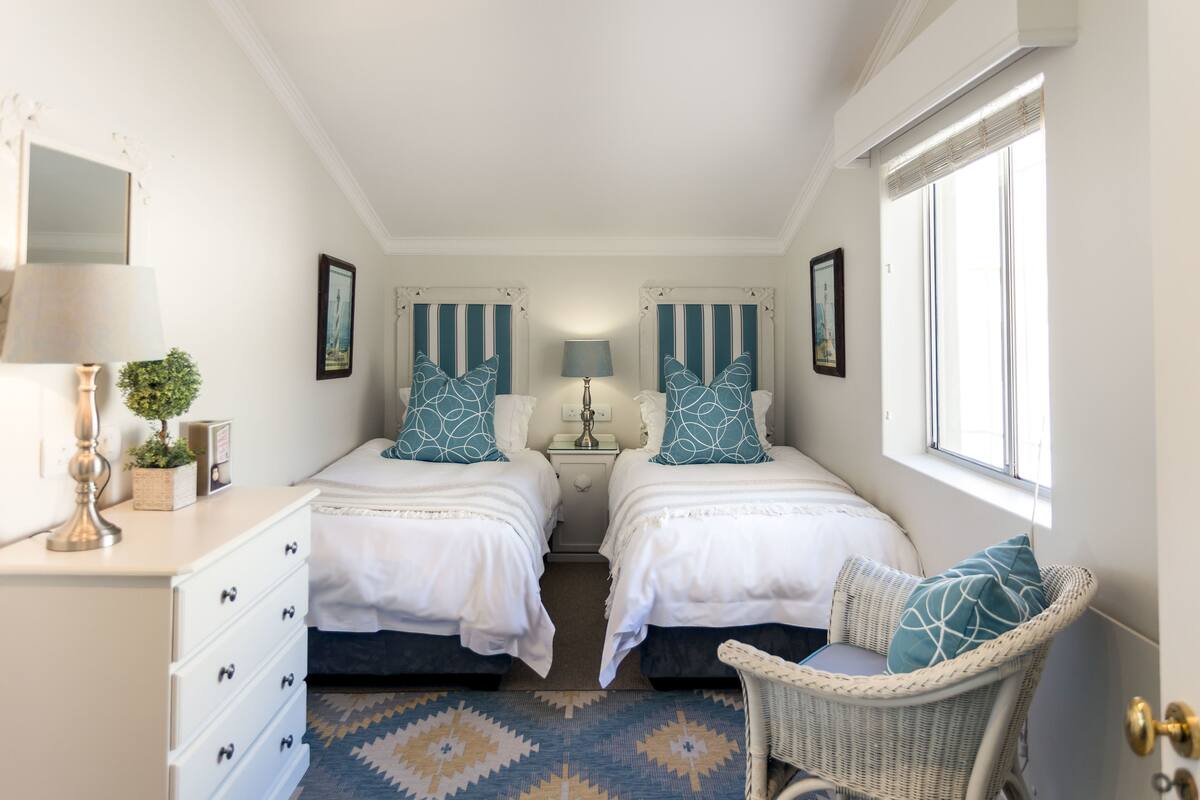 A bedroom with two beds, a dresser, a chair, and a window.