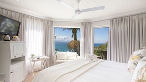 Habitación de hotel con una cama grande, televisión, escritorio con silla y vistas al océano.