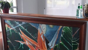 Un comptoir d’accueil orné d’un tableau encadré, d’une plante en pot et d’une fenêtre avec des stores.