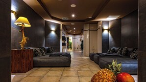 A modern lobby with dark walls, a wooden side table, a sofa, and a fruit bowl. - Schloss Hotel Holzrichter (Nachrodt-Wiblingwerde)