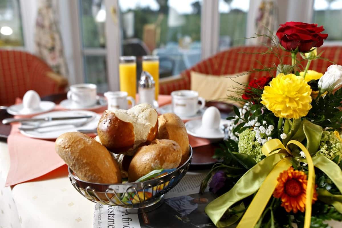 Een ontbijttafel met brood, sap en bloemen.