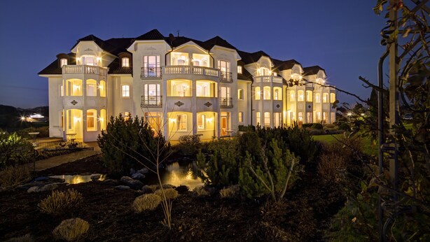 A large, multi-story house with multiple balconies and a well-lit exterior at night. - Schloss Hotel Holzrichter (Nachrodt-Wiblingwerde)
