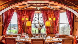 A dining area with a round table set for six, surrounded by wooden chairs with patterned cushions. - Schloss Hotel Holzrichter (Nachrodt-Wiblingwerde)