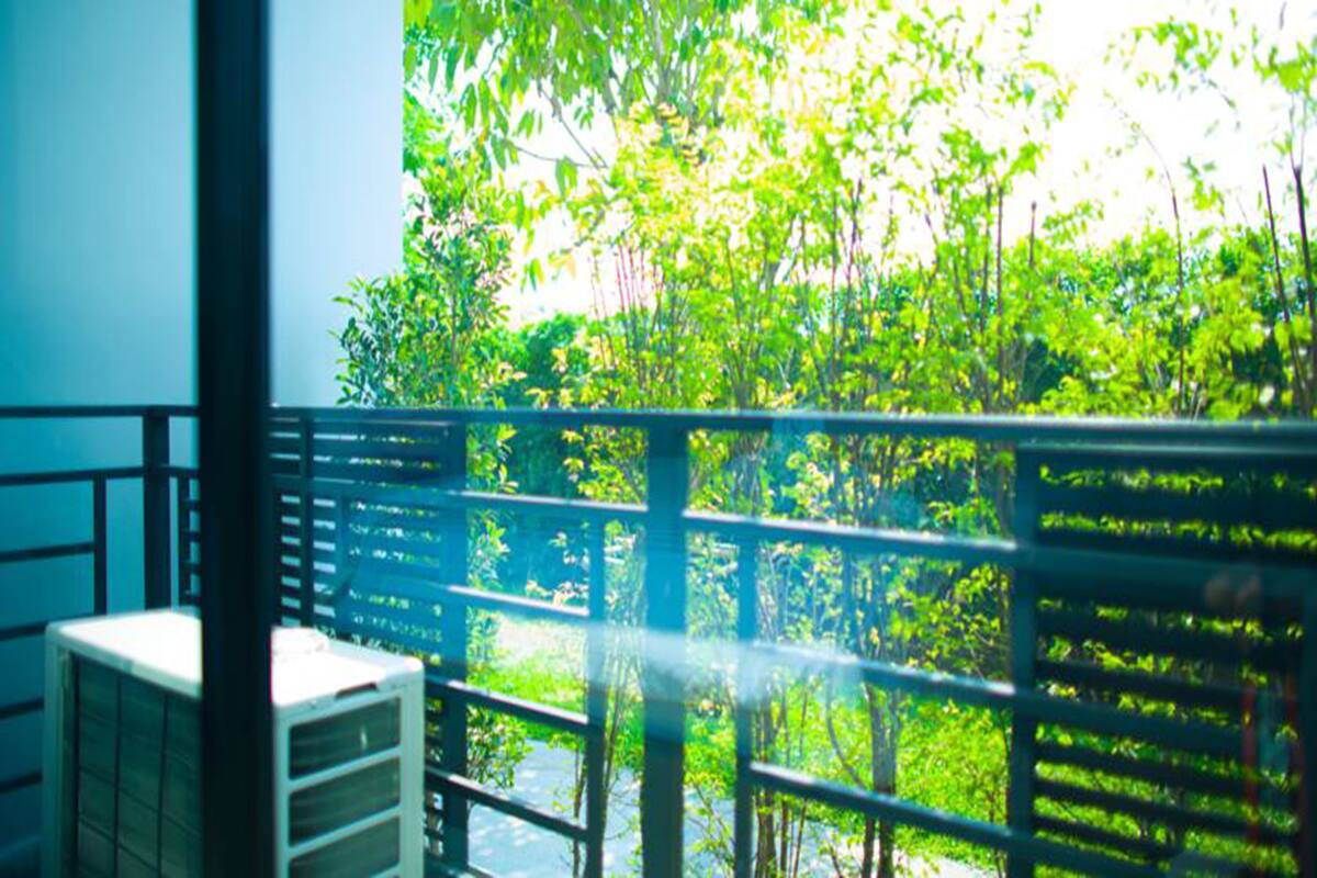 A balcony with a view of dense greenery and a metal railing.