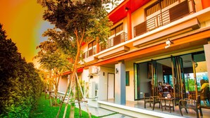 Un hotel moderno con una zona de estar cubierta al aire libre, unidades de aire acondicionado y un jardín bien cuidado.