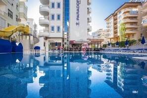 Una piscina al aire libre, sombrillas, sillones reclinables de piscina