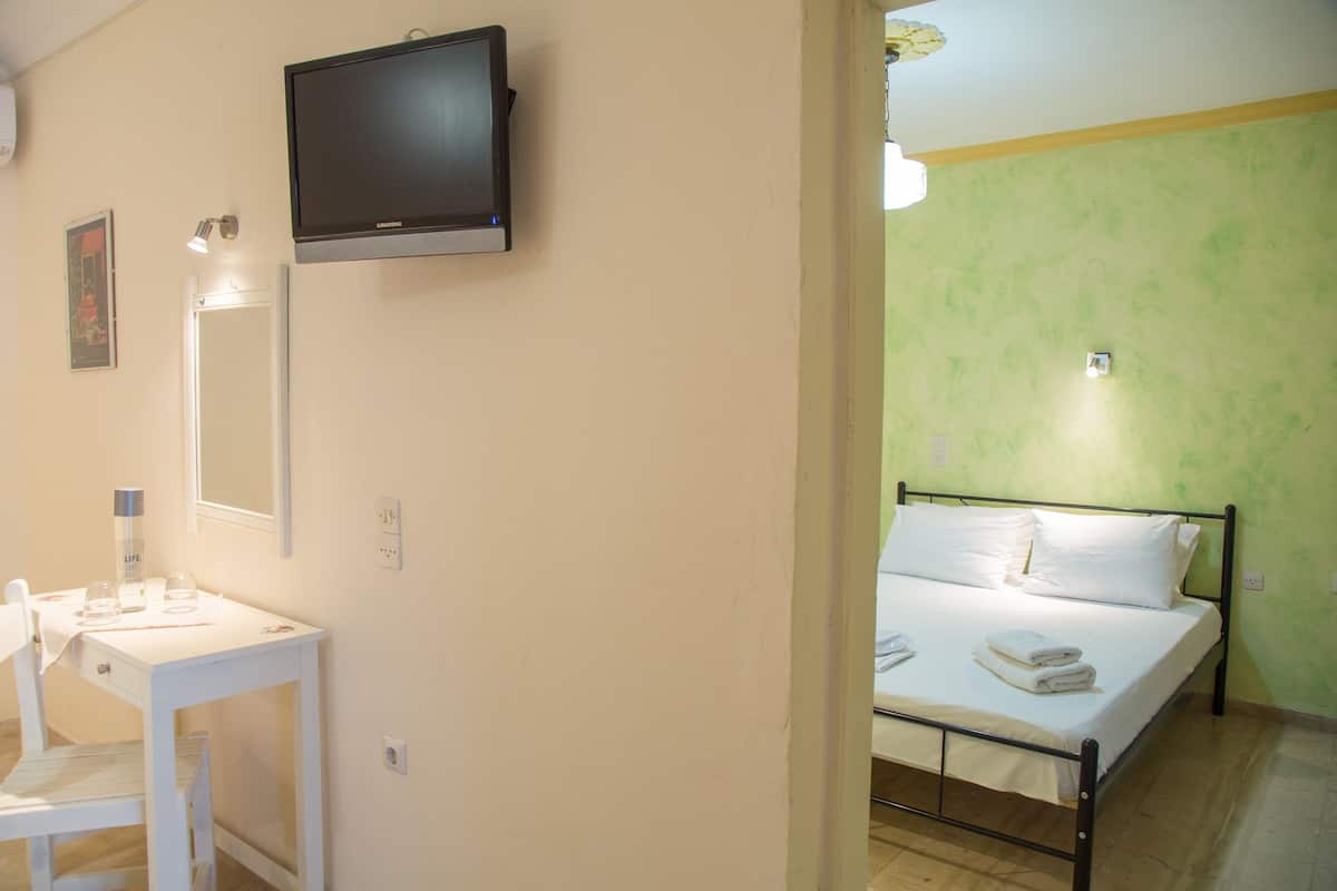 A room with a bed, a desk, a mirror, and a TV.