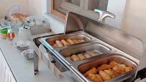 A buffet setup with multiple food stations including a croissant station and a coffee station. - Aristides Studios (Corfu)