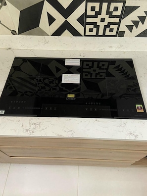 A kitchen with a black and white backsplash, a marble countertop, and a black induction cooktop labeled 'Faster'. - Sunny Saigon Apartments & Hotel (Ho Chi Minh City)