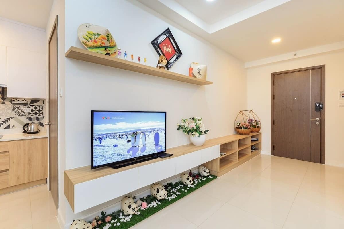 Una sala de estar moderna con un televisor de pantalla plana, estanterías de madera y objetos decorativos.