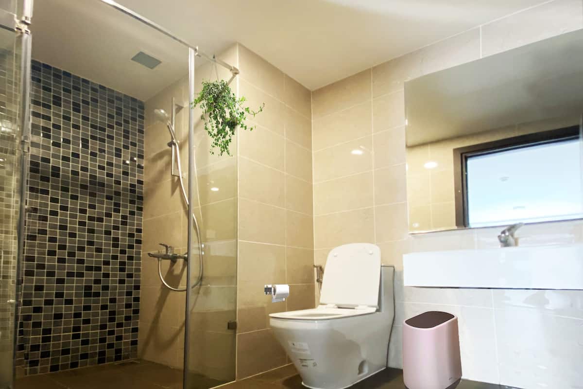 Un baño moderno con cabina de ducha de vidrio, inodoro y lavamanos.