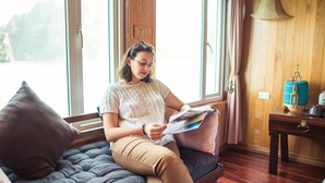 Une personne assise sur un banc rembourré, en train de lire un magazine.