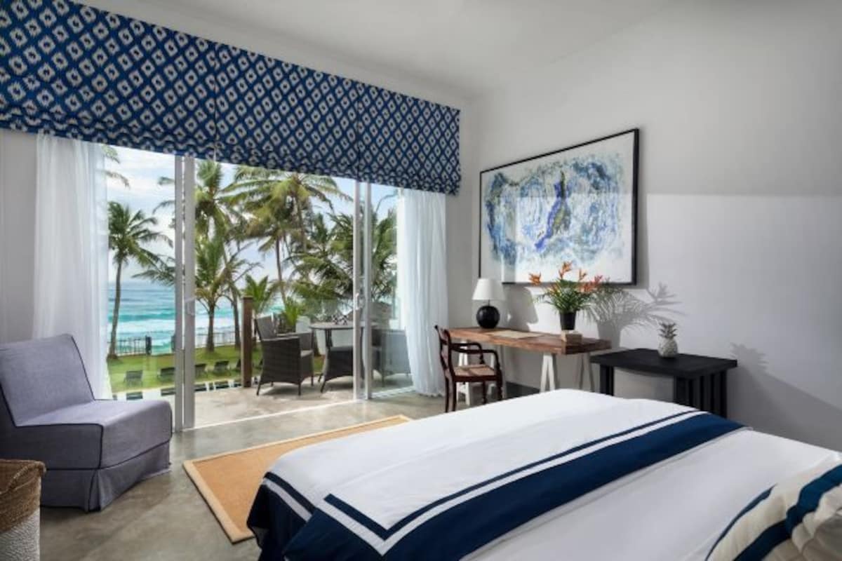 Una habitación de hotel con cama, escritorio, silla y vista al océano.