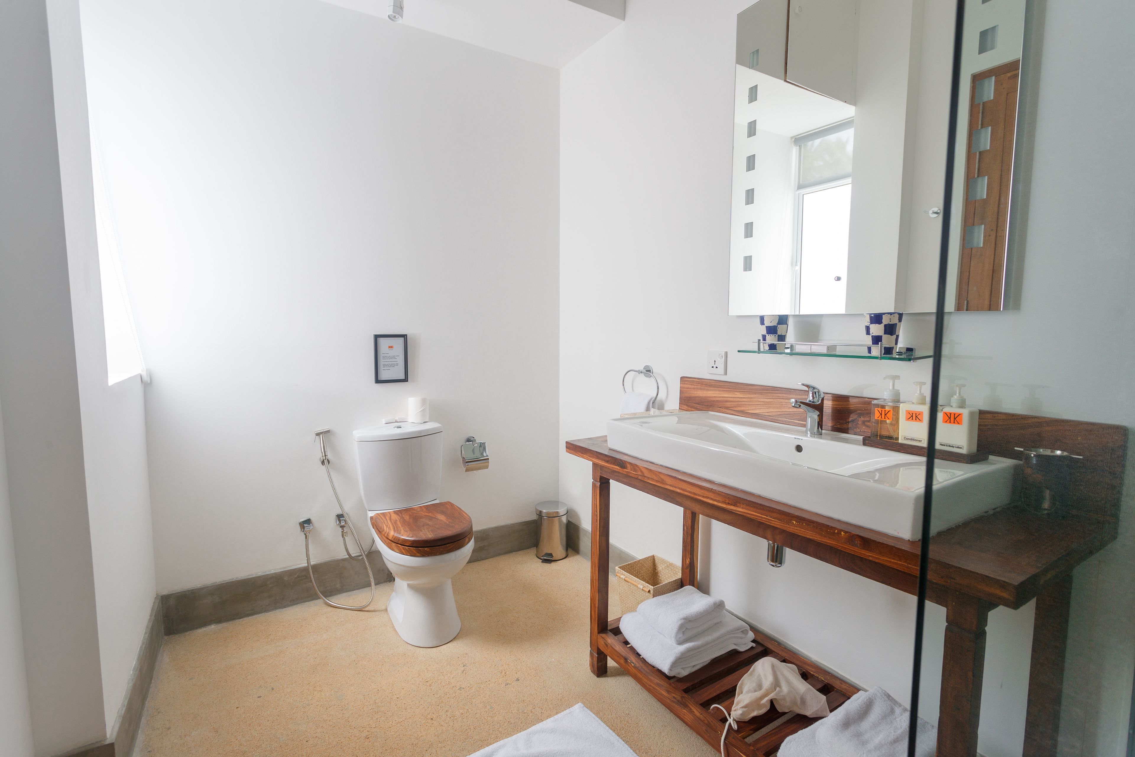 Ein modernes Badezimmer mit Toilette, Holzwaschtisch und großem Spiegel.