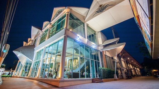 Un hôtel moderne doté d’une façade en verre, de plusieurs étages et d’une entrée imposante surmontée d’un auvent.