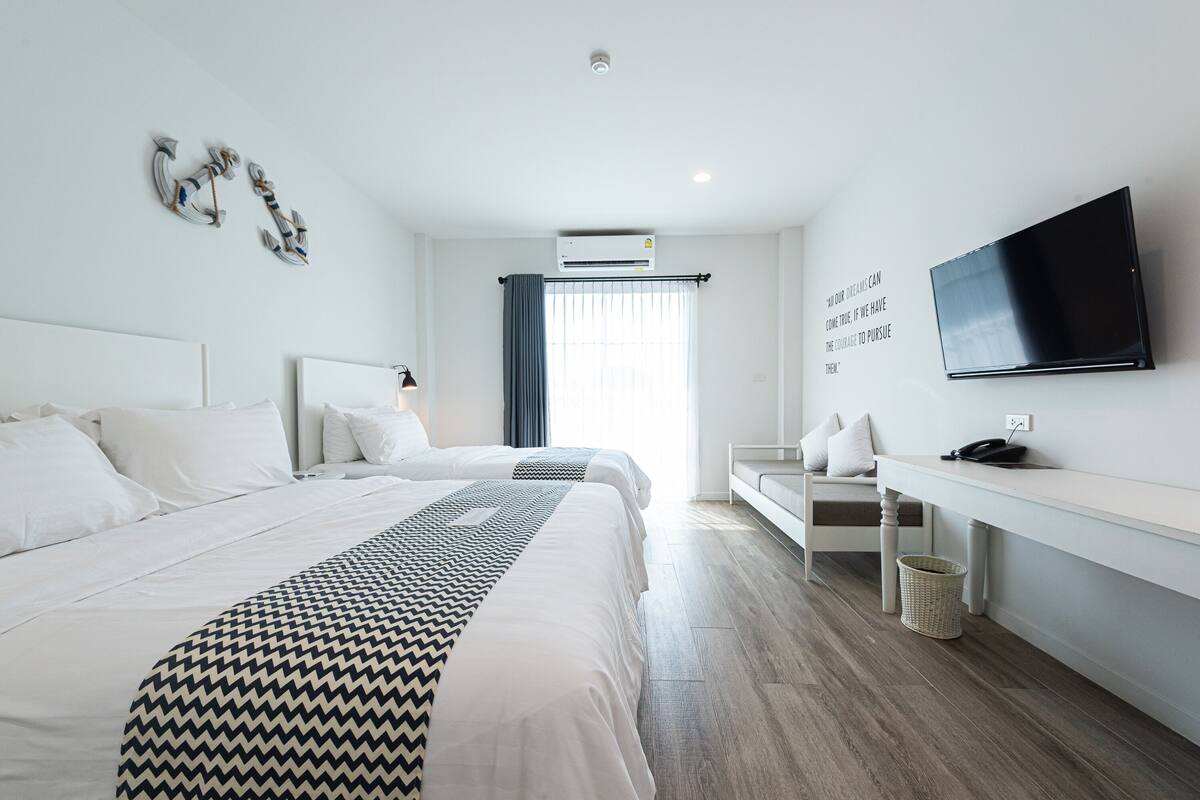 Une chambre d’hôtel moderne dotée d’un grand lit, d’un bureau avec un téléviseur à écran plat et d’une fenêtre avec des rideaux.