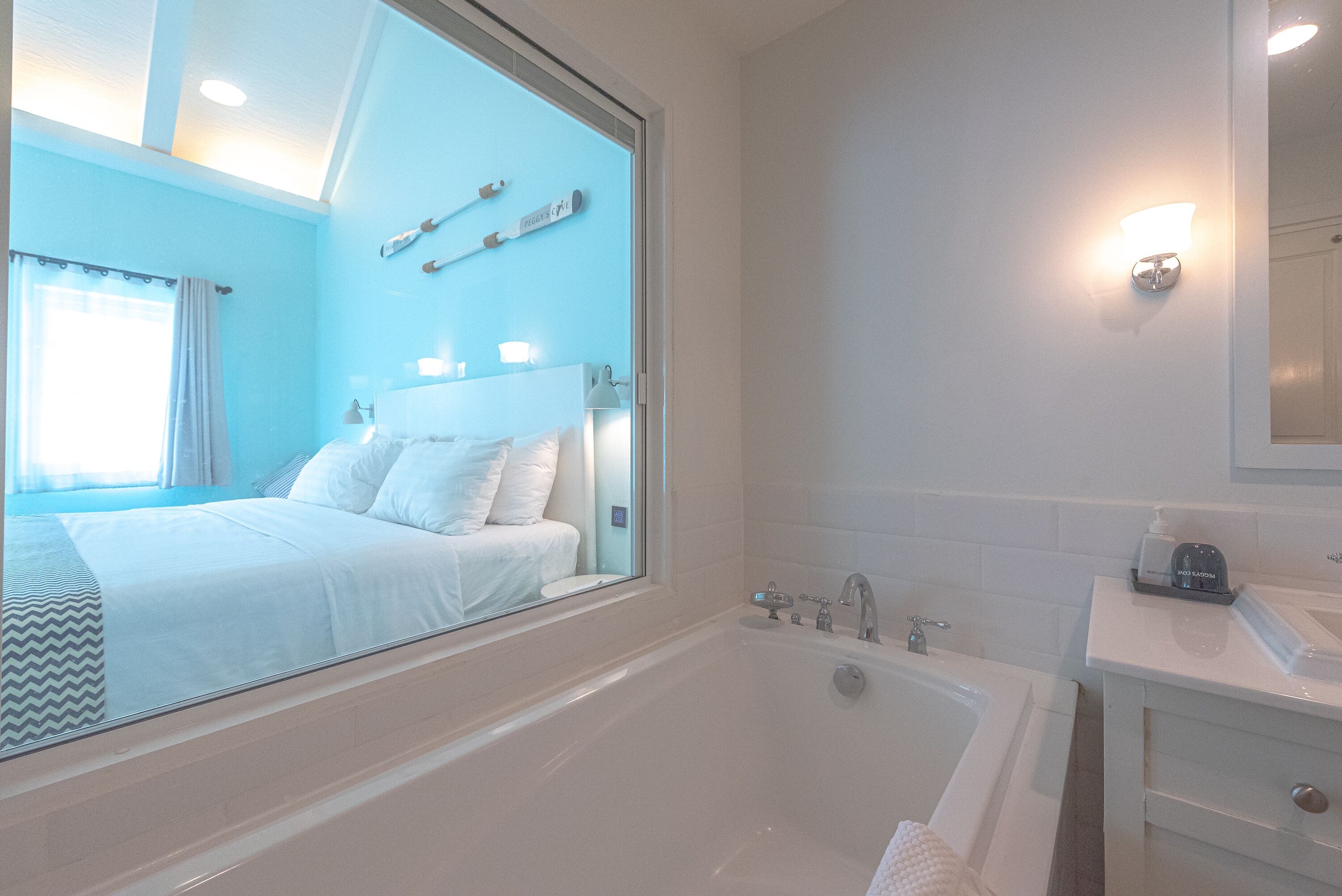 A modern bathroom with a large bathtub, a vanity with a mirror, and a bed with white linens.