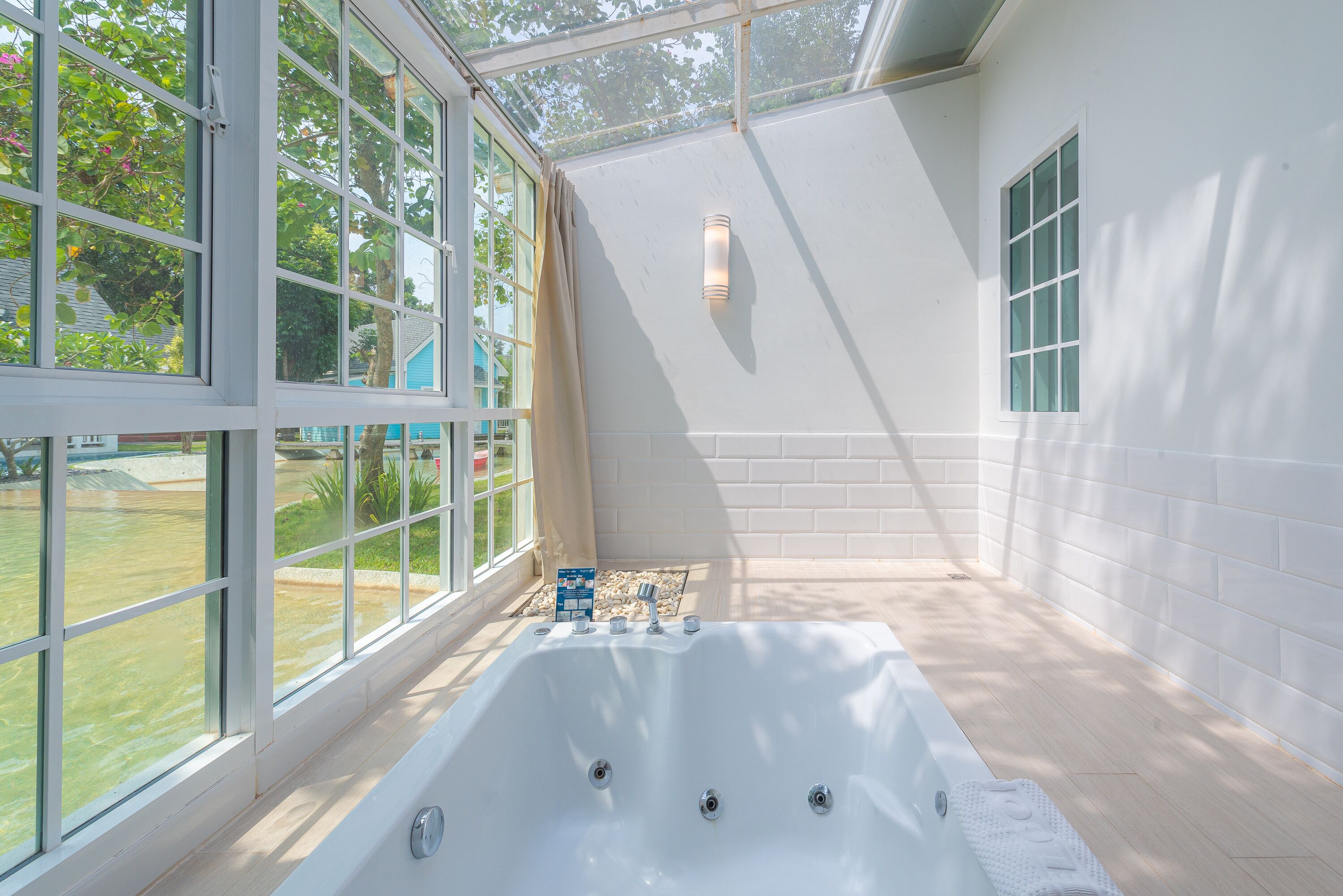 A modern bathroom with a large bathtub, a glass enclosure, and a view of the outdoors.