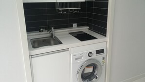 Uma cozinha compacta com pia, fogão embutido e máquina de lavar com abertura frontal.
