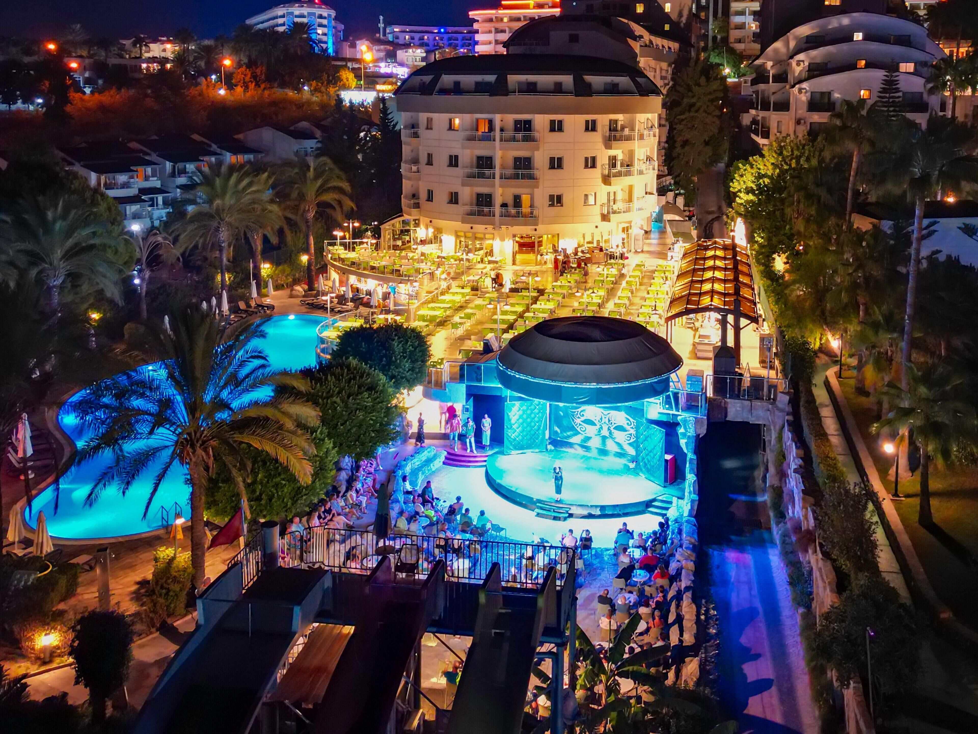 A hotel with a pool, outdoor seating, and a stage for events.